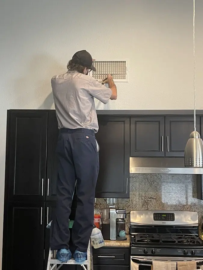 Technician inspecting an air vent during HVAC service in Sugar Grove